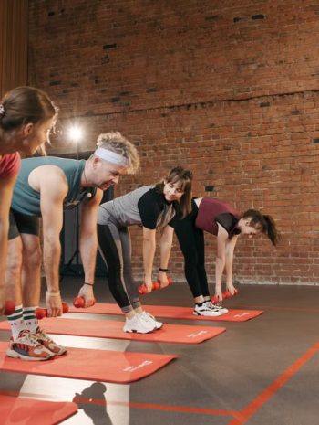 Fitness group performing exercises with dumbbells in a modern yoga studio setting.