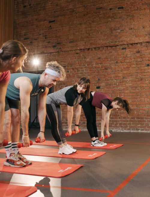 Fitness group performing exercises with dumbbells in a modern yoga studio setting.