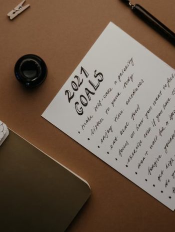 Stylish flat lay of a 2021 goals list with stationery on a brown background.