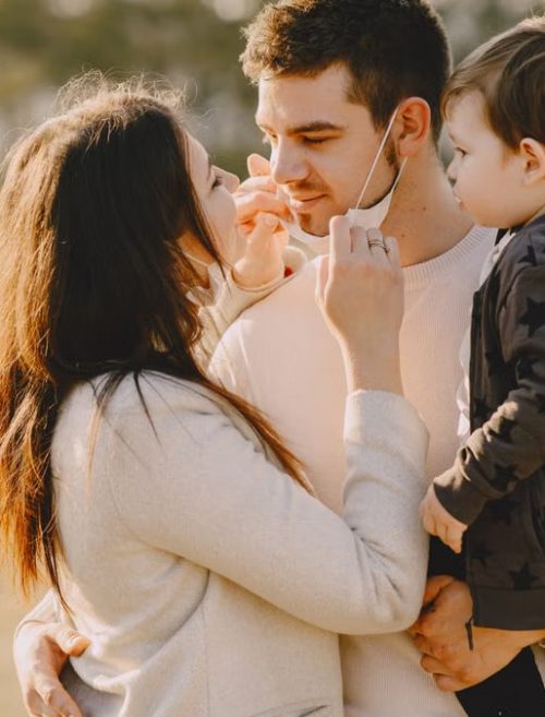 Family sharing affectionate moments outdoors with parents and child enjoying the sunny day.